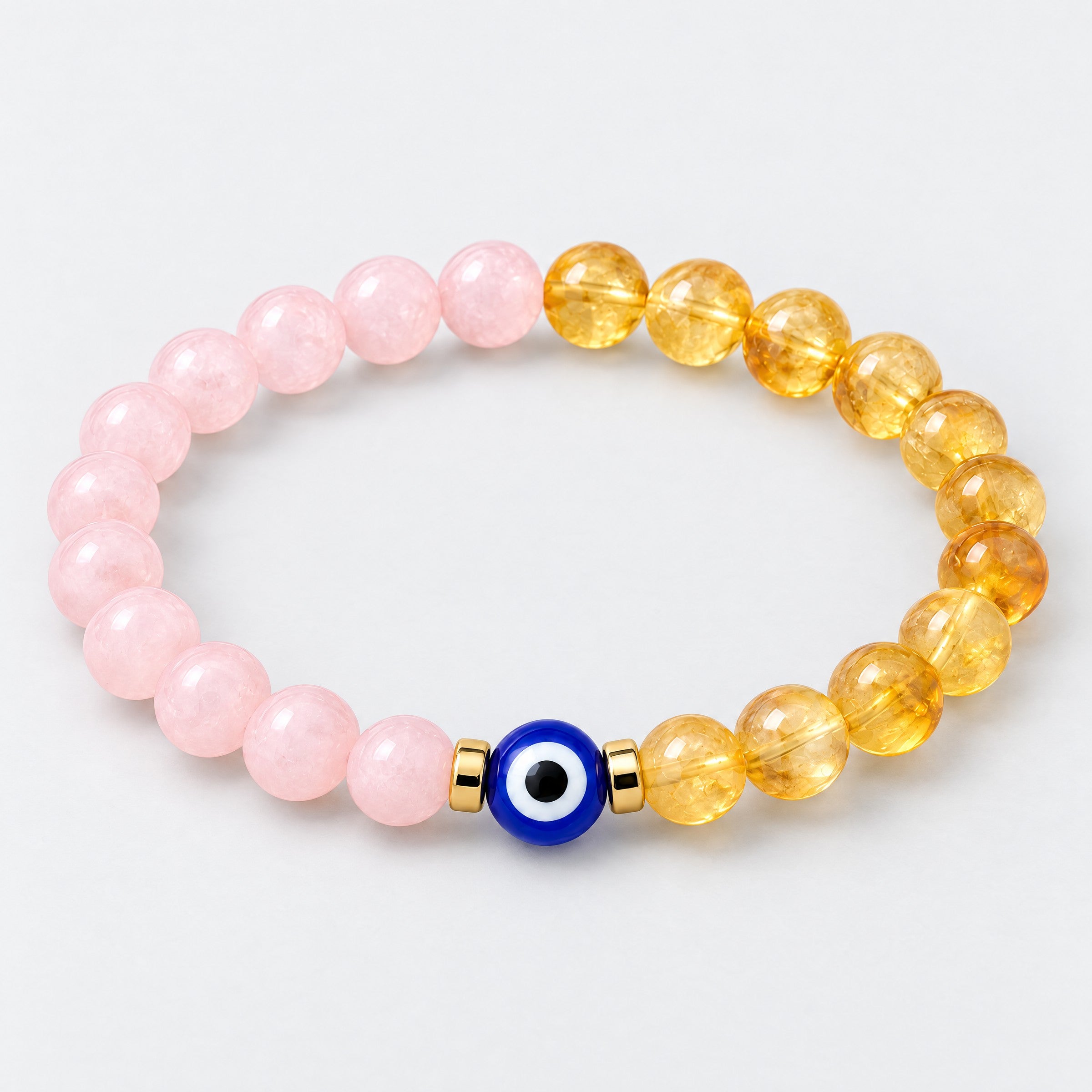 Half pink rose quartz and half golden citrine stretch bracelet with a blue evil eye bead and gold-tone spacers on a light background.