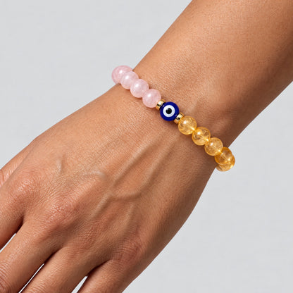 Rose quartz and citrine evil eye bracelet worn on a wrist with the blue eye bead centered between the two stone halves.